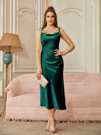 a woman in a green dress standing in front of a couch