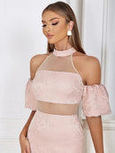 a woman wearing a pink dress with sheer shoulders