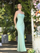 a woman in a green dress standing in front of flowers