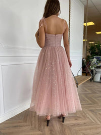 a woman in a pink dress standing on a wooden floor