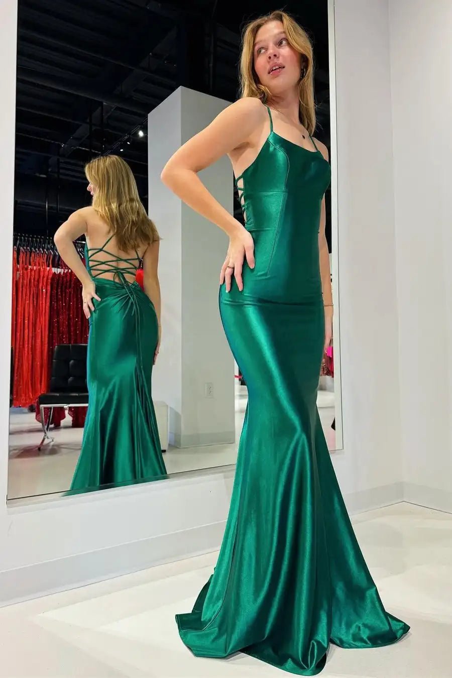 a woman in a green dress standing in front of a mirror