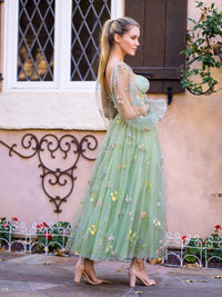 a woman in a green dress standing in front of a building