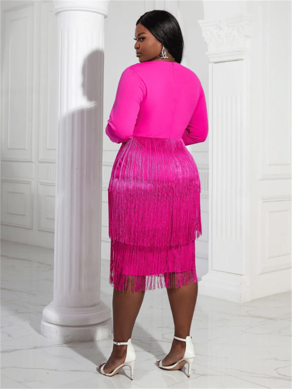 a woman in a pink dress standing next to a column