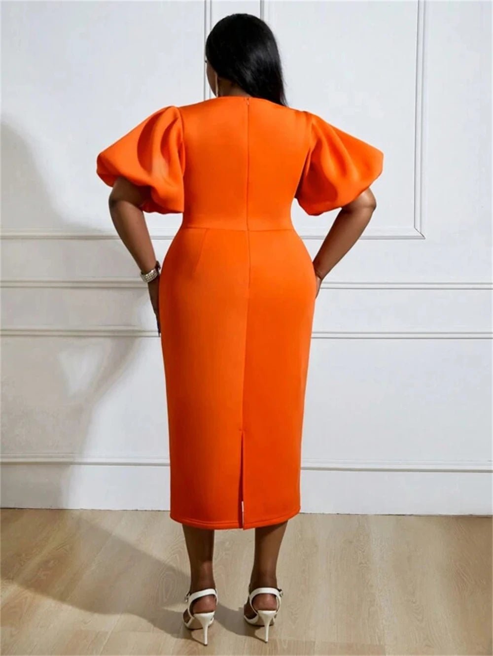 a woman in an orange dress standing in front of a wall