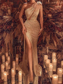 a woman in a gold dress standing in front of candles