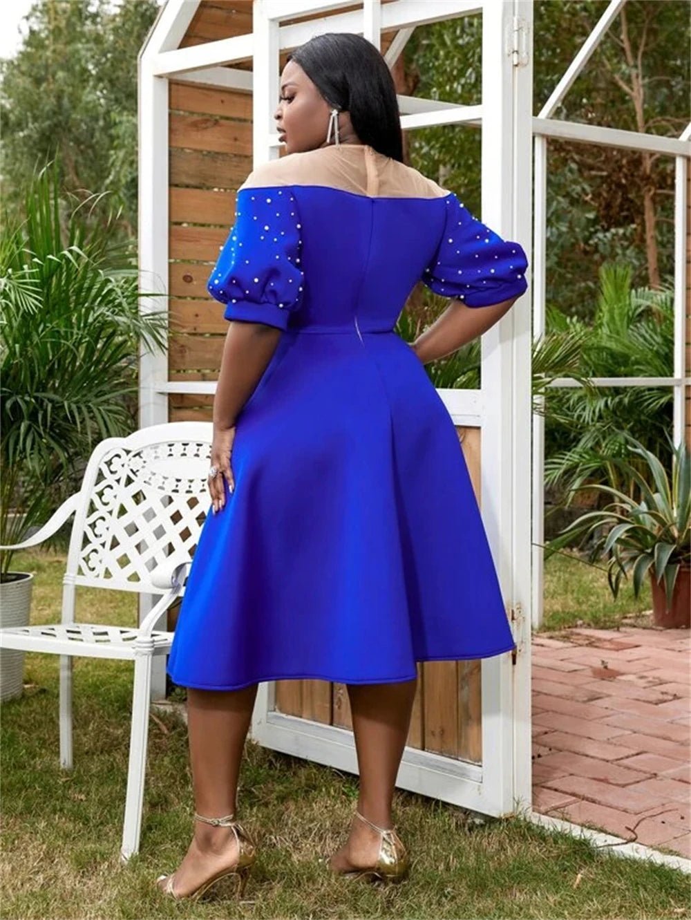 a woman in a blue dress standing next to a white chair