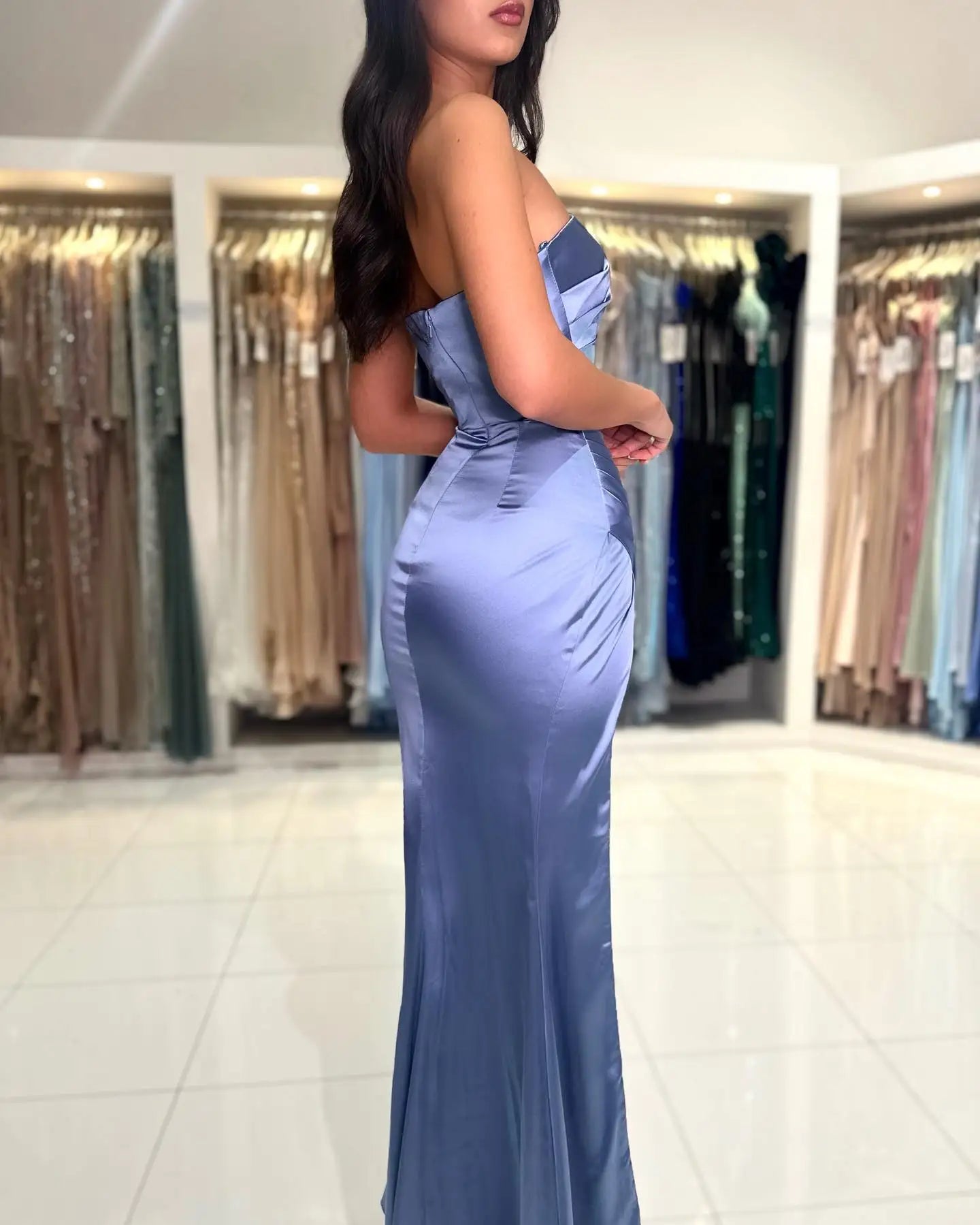 a woman in a blue dress standing in front of a rack of dresses