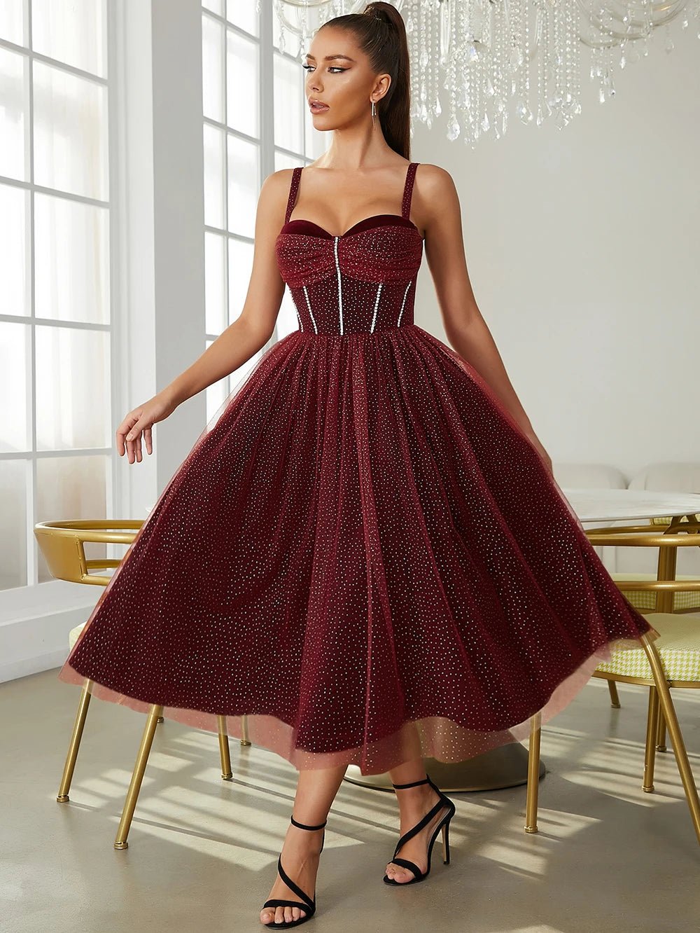 a woman in a red dress standing in front of a chandelier