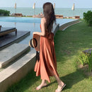 a woman in an orange dress is walking by a pool