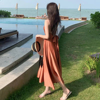 a woman in an orange dress is walking by a pool